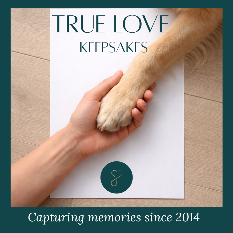 True Love Keepsake text at the top with an image of a hand holding a dog's paw. Both rest on white paper with a light wooden background.